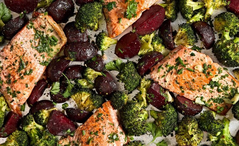 Filés de salmão assados com brócolis e beterraba em uma assadeira.