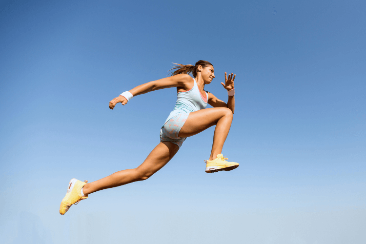 Treino de Potência para Longevidade: Saltar e Correr 2 Mulher saltando com roupa esportiva contra céu azul.