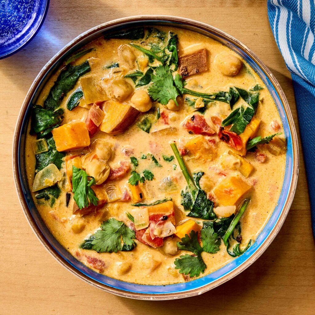 Prato de curry colorido com grão-de-bico, legumes e ervas frescas.