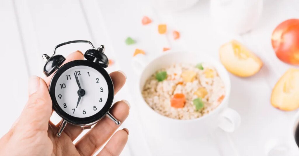 person s hand holding alarm clock hand breakfast table