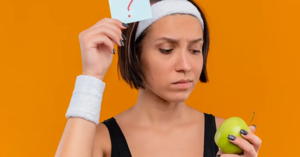 young fitness woman sportswear with headband holding reminder paper with question mark green apple l